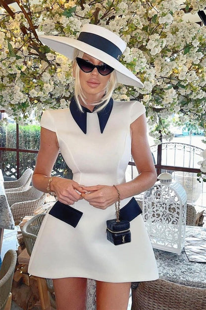 Woman in white mini dress with black collar and pockets